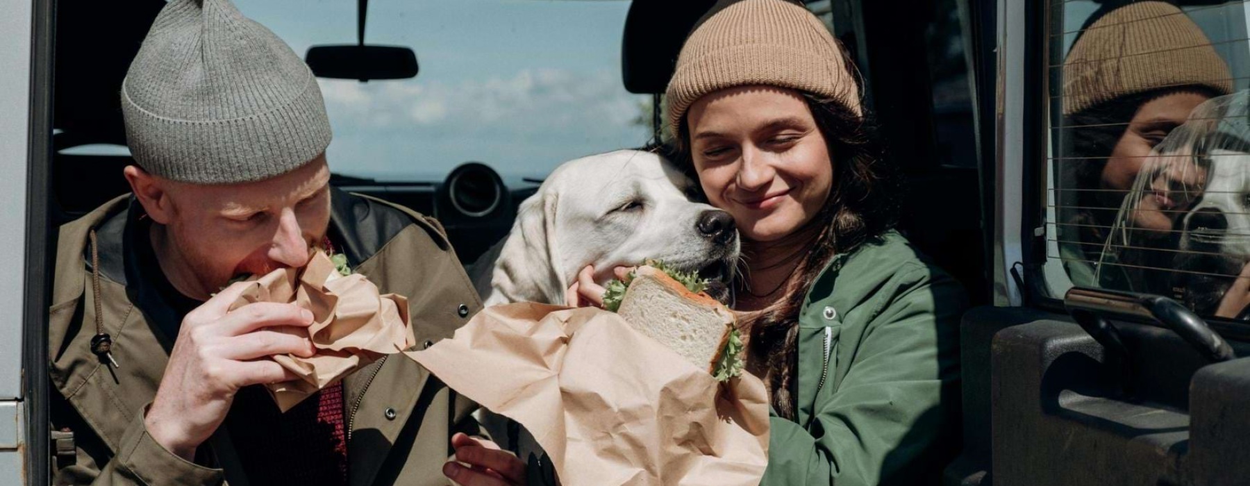 a man and woman eating food in a car