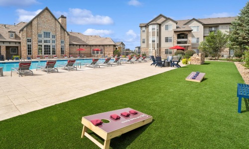 a cornhole area with chairs and tables and a pool
